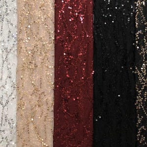May include: Close-up of five different fabrics with sequin embellishments. The fabrics are white, beige, burgundy, black, and dark gold. The sequins are arranged in a scattered pattern, creating a shimmering effect. Ideal for dresses, skirts, and other apparel.