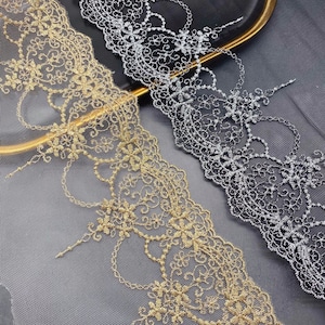 May include: Two pieces of gold and silver lace trim with a delicate floral pattern. The lace is on a sheer mesh background.