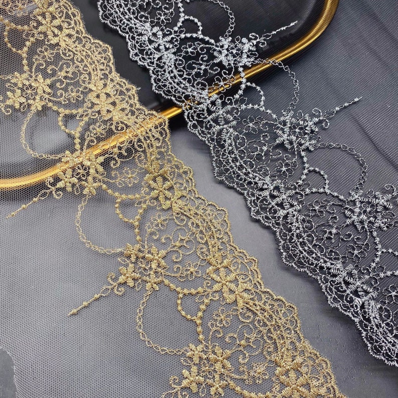 May include: Two pieces of gold and silver lace trim with a delicate floral pattern. The lace is on a sheer mesh background.