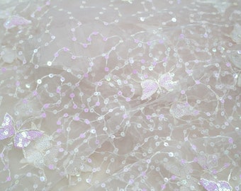 May include: White tulle fabric with iridescent sequins and pink butterfly embellishments.