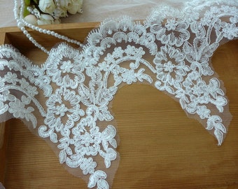 May include: White lace trim with a scalloped edge and floral design. The lace is delicate and intricate, with small flowers and leaves.