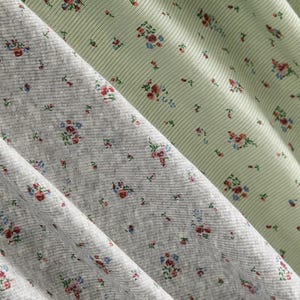 Pu&ograve; includere: Primo piano di tre tessuti con motivi floreali. I tessuti sono in tonalit&agrave; di grigio e verde chiaro. Il tessuto grigio ha una trama a coste ed &egrave; ricoperto da piccoli gruppi floreali in rosso, blu e rosa. Il tessuto verde chiaro ha un motivo a righe e gruppi floreali simili.