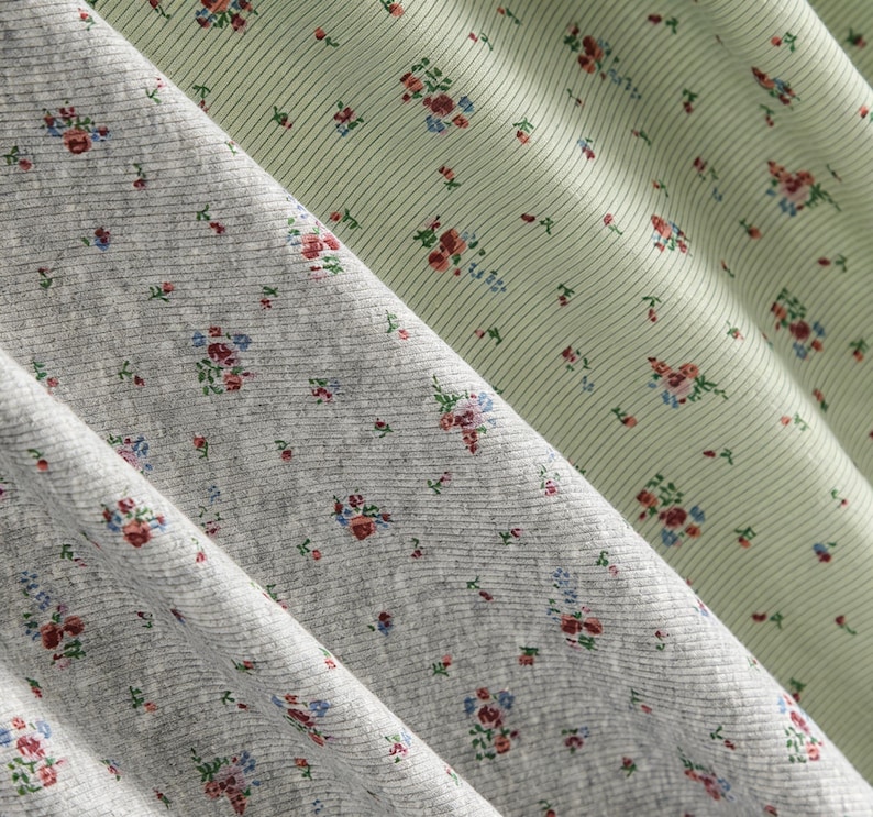 Pu&ograve; includere: Primo piano di tre tessuti con motivi floreali. I tessuti sono in tonalit&agrave; di grigio e verde chiaro. Il tessuto grigio ha una trama a coste ed &egrave; ricoperto da piccoli gruppi floreali in rosso, blu e rosa. Il tessuto verde chiaro ha un motivo a righe e gruppi floreali simili.