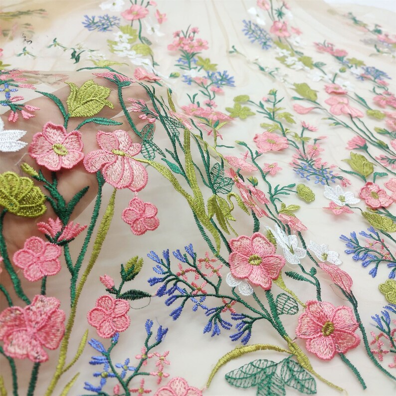May include: Beige sheer fabric with embroidered pink, white, and blue flowers and green leaves.