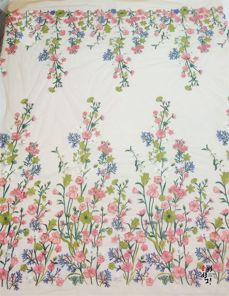 May include: White floral embroidered fabric with pink, green, and blue flowers. The fabric has a sheer, mesh-like texture.