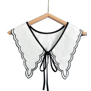 May include: White faux collar with a black scalloped trim and a black ribbon tie.