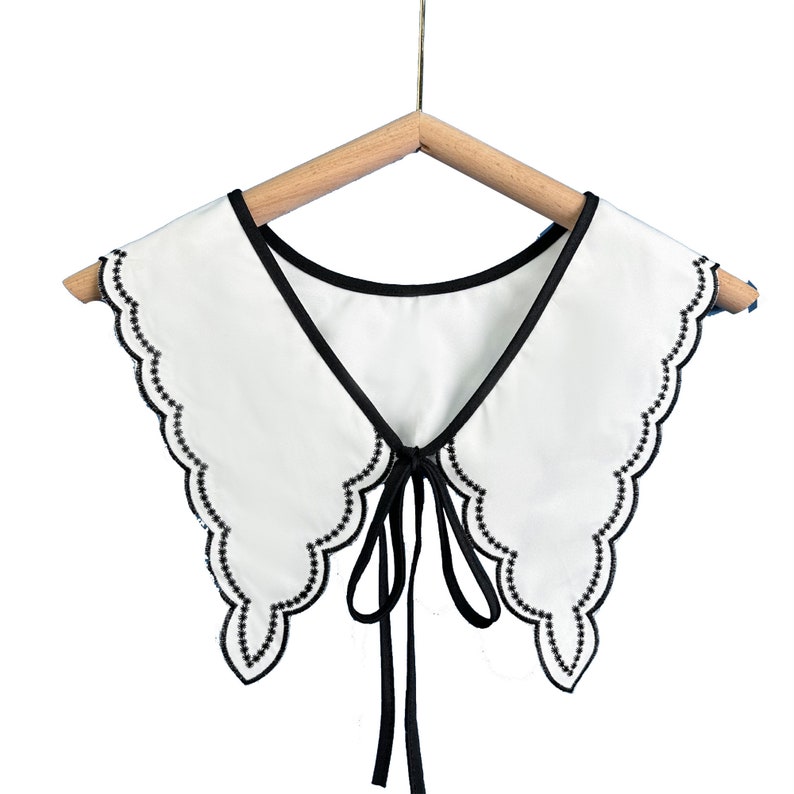 May include: White faux collar with a black scalloped trim and a black ribbon tie.