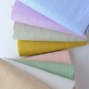 May include: A stack of six different colored ribbed fabrics with a delicate lace pattern. The colors are light blue, lavender, beige, yellow, pink, and green.