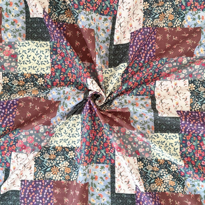 Puede incluir: Una tela de patchwork que presenta una variedad de patrones florales en tonos burdeos, azul marino, crema y azul claro. El tejido muestra una cuadr&iacute;cula repetitiva de cuadrados con diversos estampados bot&aacute;nicos, incluyendo peque&ntilde;as margaritas.