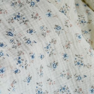 May include: White fabric with a small floral pattern in shades of blue and pink.