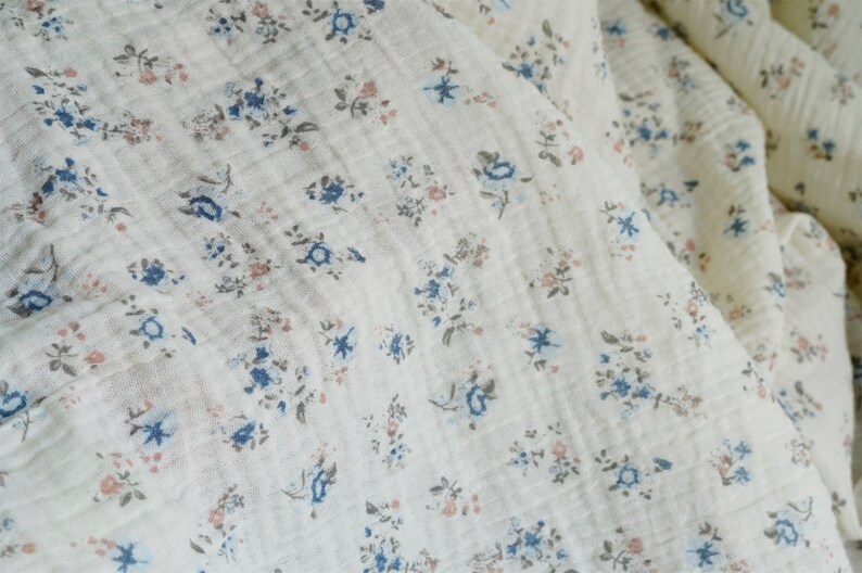 May include: White fabric with a small floral pattern in shades of blue and pink.