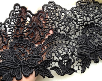 May include: Black lace trim featuring a delicate floral design. The lace has a scalloped edge and is ideal for adding a touch of elegance to any project.