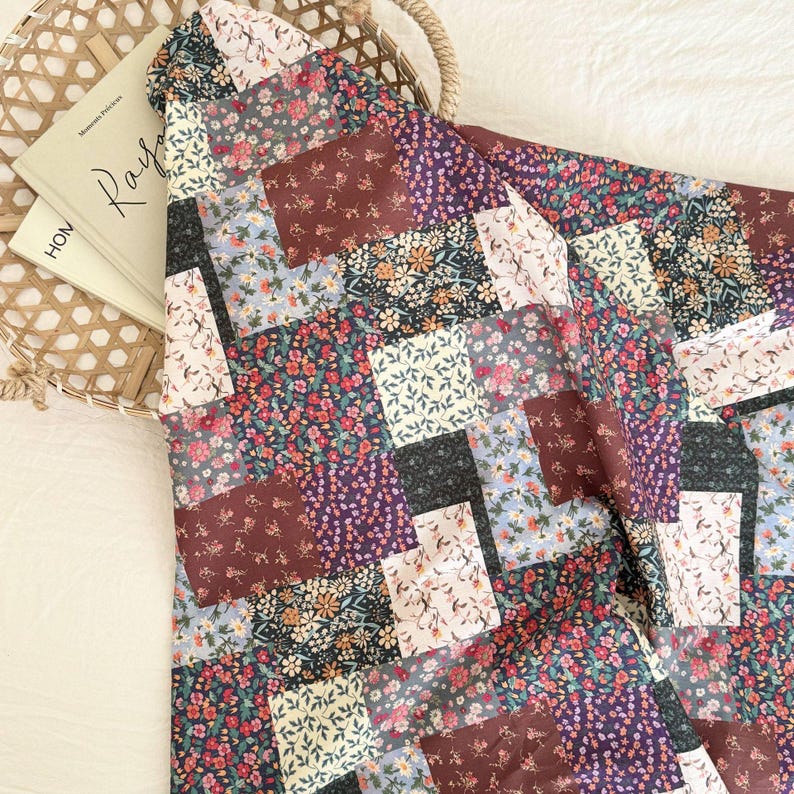 Puede incluir: Un tejido textil con un dise&ntilde;o de patchwork compuesto por varios segmentos rectangulares. Cada segmento muestra un patr&oacute;n floral distinto en una paleta de colores burdeos intenso, azul marino, azul claro, crema y rosa suave con hojas verdes.