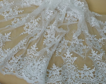 Könnte beinhalten: Weißer Spitzenstoff mit floralen und Blattmustern. Die zarte Spitze ist halbtransparent und weist detaillierte Stickereien auf. Geeignet für Brautmode, Kleider oder andere dekorative Projekte.