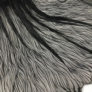 May include: Black lace fabric with a wavy pattern and scalloped edges.