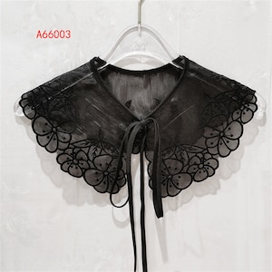 May include: A black lace collar with a floral design and a tie at the back. The collar is on a hanger and has the text "A66003" in the top left corner.