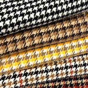 May include: Close-up of several fabric samples with a houndstooth pattern. The fabrics are in various colors, including black and white, brown, yellow, and red. The houndstooth pattern is a classic design often used in clothing and upholstery.