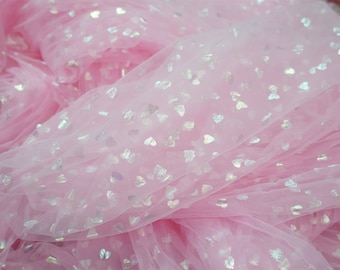 May include: Pink tulle fabric with scattered silver heart-shaped sequins. The fabric is gathered and layered, creating a soft, flowing appearance. Ideal for crafting or decorative purposes.