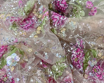 May include: A sheer beige tulle fabric featuring intricate floral embroidery in shades of vibrant pink, magenta, and green. The material is embellished with scattered iridescent sequins that catch the light, creating a textured and shimmering surface.