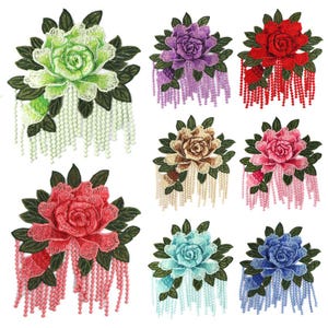 May include: A collection of eight embroidered flower patches featuring roses in various colors including green, purple, red, beige, pink, light blue, and dark blue. Each patch includes dark green leaves and hanging beaded fringe strands.