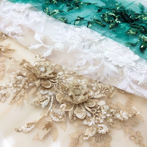 May include: Three layers of lace fabric with sequins. The top layer is a green lace, the middle layer is a white lace, and the bottom layer is a gold lace with floral designs.