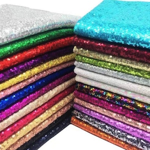 May include: A collection of folded fabric squares covered in shimmering sequins, arranged in two stacks. The fabric pieces feature a wide variety of vibrant colors including silver, green, red, gold, blue, purple, pink, black, and turquoise.