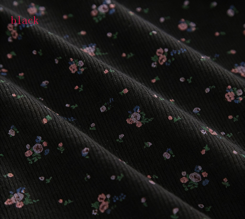 Pu&ograve; includere: Primo piano di tessuto nero con motivo floreale. Il tessuto ha una trama a coste ed &egrave; adornato da piccoli disegni floreali sparsi in tonalit&agrave; di rosa, blu e verde. La parola "black" &egrave; visibile nell'angolo in alto a sinistra.