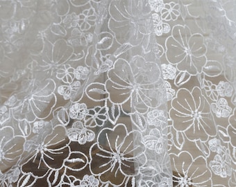 May include: White floral lace fabric with a delicate embroidered pattern. The lace is sheer and lightweight, making it perfect for a variety of crafting projects.