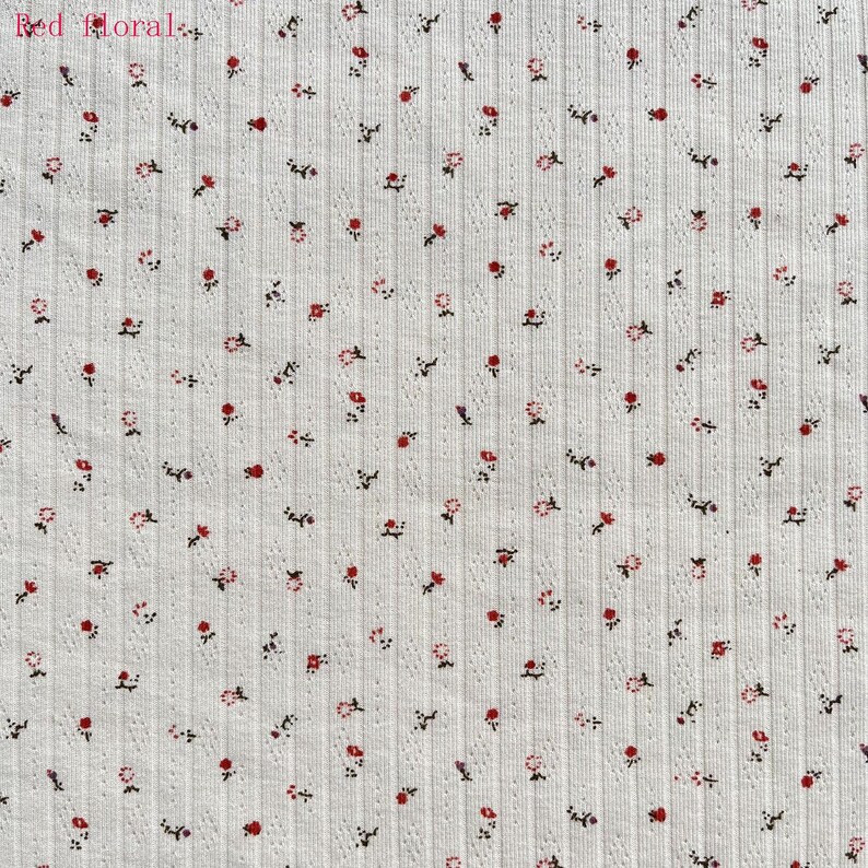 May include: White ribbed fabric with a repeating pattern of small red and pink flowers and dark green stems. The text "Red Floral" is in the upper left corner. The fabric has a textured, vertical striped design.