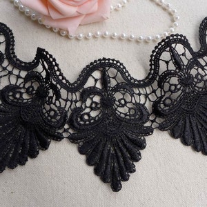 May include: Black lace trim with a scalloped edge and intricate floral designs. The lace is delicate and has a soft, flowing texture.