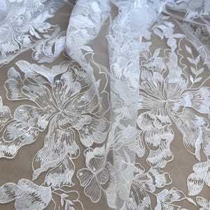 May include: White floral lace fabric with sequins. The lace features a delicate floral pattern with a sheer background.