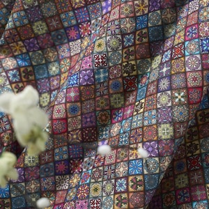 May include: A fabric featuring a repeating grid pattern of small squares, each containing a unique, intricate floral or geometric mandala-style design in a vibrant palette of blue, purple, red, yellow, and white, with soft folds creating depth.