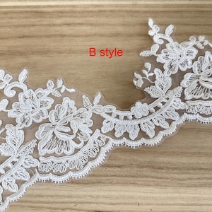 May include: White floral lace trim with a scalloped edge. The lace features detailed embroidered flowers and leaves. The text "B style" is in red. Ideal for embellishing garments or crafts.