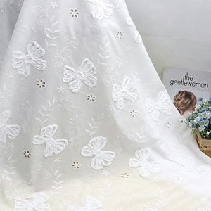 Op de afbeelding: Witte transparante gordijn met geborduurde vlinder- en bloempatronen. Het gordijn heeft delicate uitgesneden details en een vloeiend, luchtig ontwerp, perfect om een vleugje elegantie aan elke kamer toe te voegen.