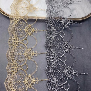 May include: Two pieces of gold and silver lace trim with a delicate floral pattern. The lace is on a sheer mesh background.
