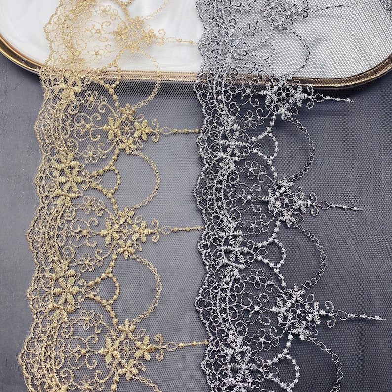 May include: Two pieces of gold and silver lace trim with a delicate floral pattern. The lace is on a sheer mesh background.