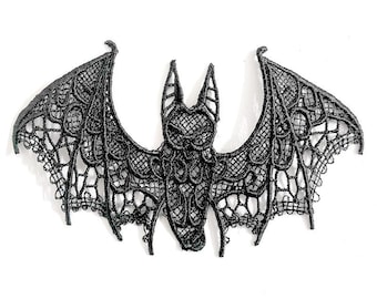 May include: A black lace bat with detailed openwork patterns. The bat's wings are spread wide. The decorative bat is likely for Halloween or gothic-themed decor. The lace has a textured appearance.