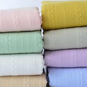 May include: A stack of six fabric swatches in various colors, including pink, green, white, beige, purple, and blue. Each swatch has a delicate lace trim and a striped pattern.