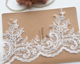 May include: White lace trim with a floral design. The lace has a scalloped edge and is decorated with small pearls. The lace is on a brown background with the text "Natural... © design by Le..."