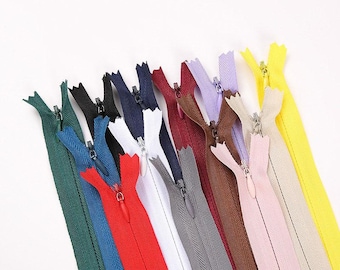 Può includere: Una collezione di cerniere colorate in varie tonalità, tra cui verde, blu, rosso, bianco, grigio, marrone, viola, rosa e giallo. Ogni cerniera ha un tirante in metallo ed è disposta su uno sfondo bianco.