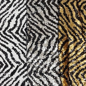 May include: Close-up of three fabrics with a chevron pattern made of sequins. The fabrics are in black and white, silver and black, and gold and black. The sequins create a shimmering, textured surface.