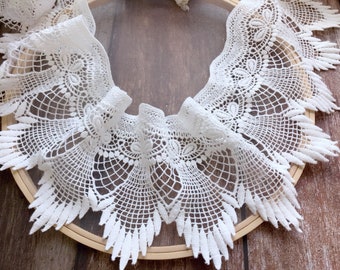 Peut inclure: Dentelle blanche avec une bordure festonnée et des motifs floraux et géométriques complexes. La dentelle est disposée en forme circulaire, mettant en valeur son design délicat. Idéale pour divers projets d'artisanat.