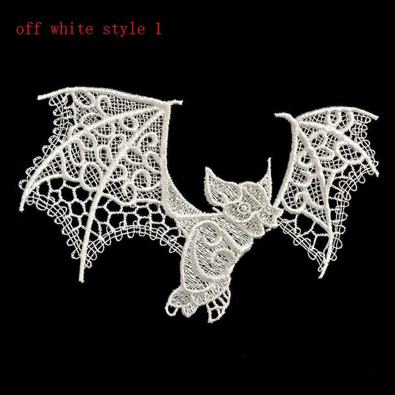 May include: Off-white lace bat applique with detailed design. The bat has outstretched wings and a detailed body, set against a black background. The text "off white style 1" is in the upper left corner.