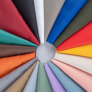 May include: A vibrant display of fabric swatches in various colors, arranged in a circular pattern. The fabrics include shades of red, blue, green, yellow, and more, radiating outwards from a central point. The image showcases a diverse palette of textiles.