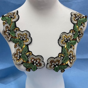May include: A pair of green, gold, and silver beaded floral appliques. The appliques are made of sequins, beads, and rhinestones. They are perfect for adding a touch of sparkle to any garment.