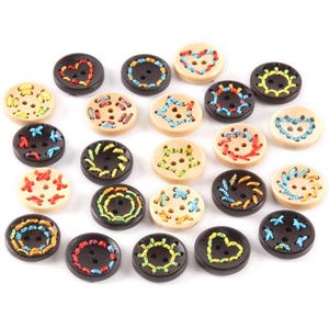 May include: A selection of decorative buttons in various colours and designs. The buttons are round with two or four holes and feature embroidered patterns like hearts, stars, and floral motifs. Some buttons are black, others are beige.