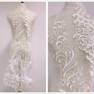 Può includere: Applique in pizzo bianco con motivi floreali e a volute. Il pizzo è su un supporto in rete ed è perfetto per aggiungere un tocco di eleganza a qualsiasi capo.