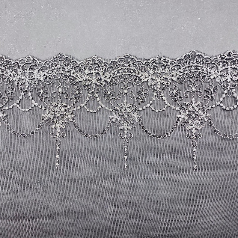 May include: Black lace trim with a delicate floral pattern and a chain-like design. The lace is soft and sheer, and it would be perfect for adding a touch of elegance to any project.