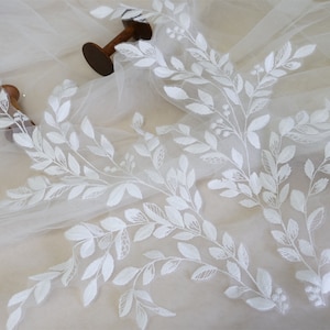 May include: White floral lace applique with delicate leaf and stem embroidery. The lace is on a sheer white fabric background.