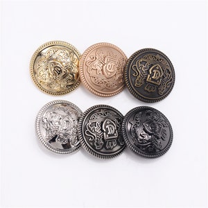 May include: Six decorative buttons with a gold, silver, and bronze finish. Each button features an intricate design with a crest and the letter "D" in the center.
